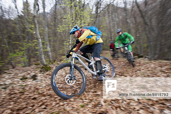 Three Mountainbikers racing through forest