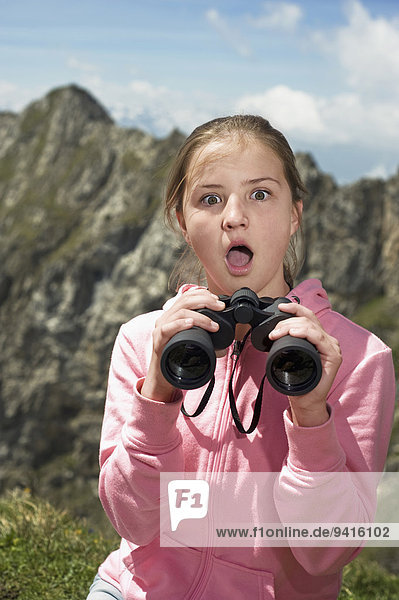 Girl holding binoculars Alps looking surprised