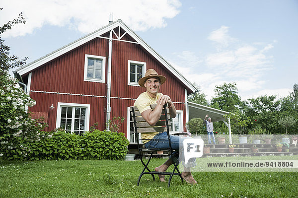Man relaxing sitting chair garden wooden house