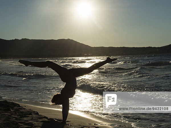 Junge Frau turnt am Strand  Gegenlicht  Korsika  Frankreich