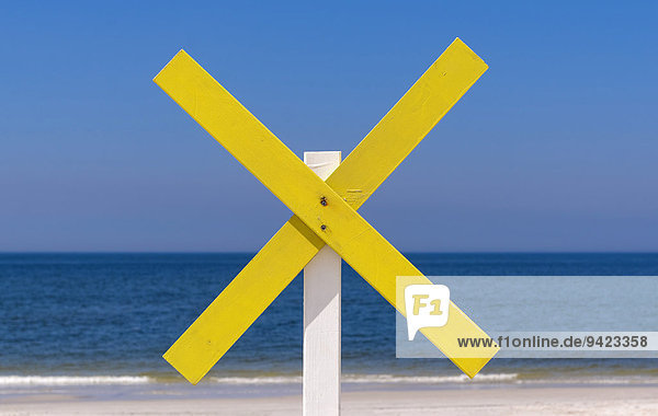 A yellow wooden cross marks a shoal near the shore at the beach  near Kampen  Sylt  Schleswig-Holstein  Germany