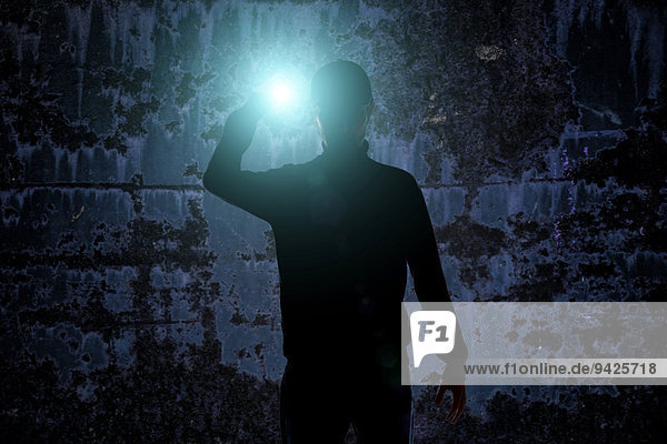 Mann mit Taschenlampe in dunkler städtischer Umgebung