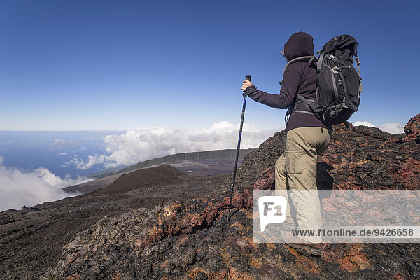 Wanderer auf Gipfel des Vulkans Piton de la Fournaise mit Ausblick auf Wolken und Meer La Reunion