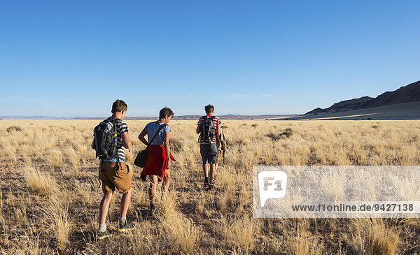 Drei Wanderer in der Savanne bei den Naukluft Bergen  Namib-Naukluft  Namibia