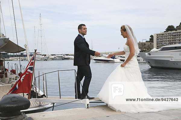 Bride and groom boarding a yacht in a marina