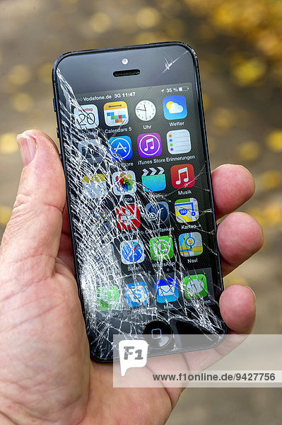 Smartphone,  iPhone 5,  mit zerbrochenem Display,  von einer Hand gehalten