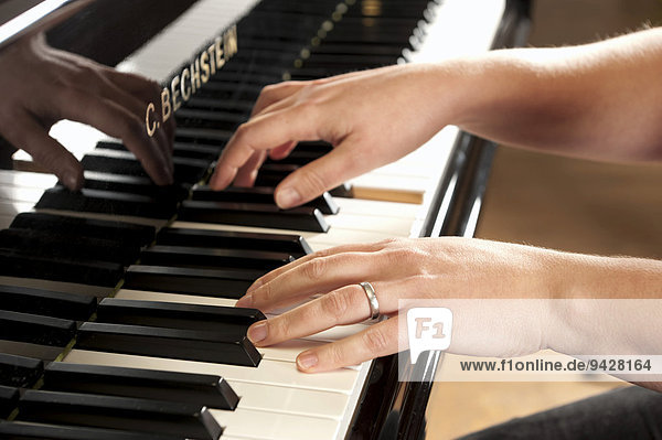 Woman's hands playing a Bechstein grand piano
