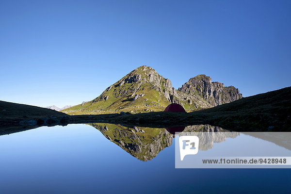 Water reflection with a tent in the mountains near Glarus in the Swiss Alps  Lake Berglimatt  Switzerland  Europe