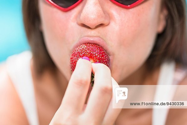 Porträt einer jungen Frau  die Erdbeere beißt