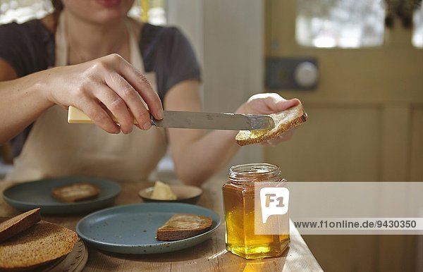 Frau probiert frisch gewonnenen Honig auf Brot