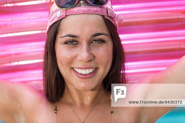 Porträt einer jungen Frau mit rosa Luftmatratze