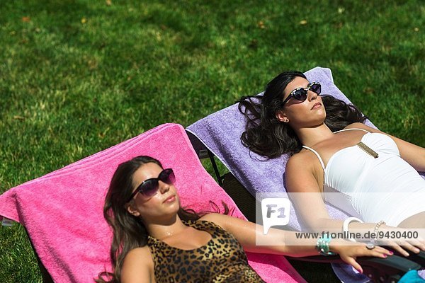 Zwei Schwestern beim Sonnenbaden auf Liegestühlen im Garten
