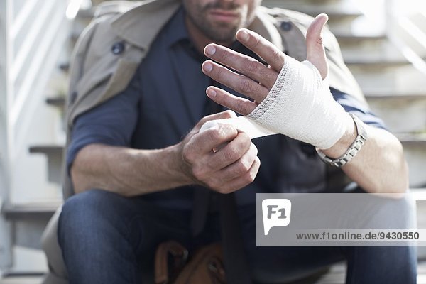 Mann bandagiert Hand auf der Treppe