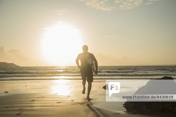 Mature man  running towards sea  holding surf board