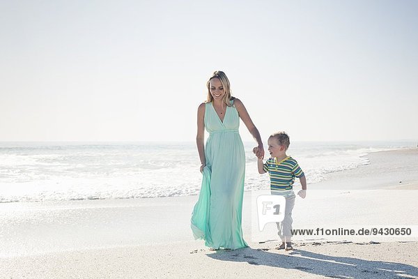 Mid adult mother and young son holding hands on beach  Cape Town  Western Cape  South Africa