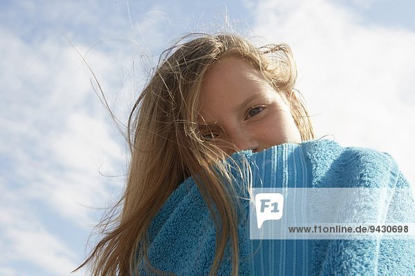 Portrait des Mädchens in Handtuch gewickelt an der luftigen Küste