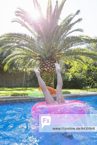 Mädchen taucht in einen aufblasbaren Ring im Gartenschwimmbad ein.