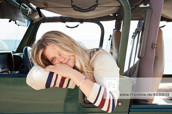 Junge Frau lehnt sich aus dem Jeepfenster.