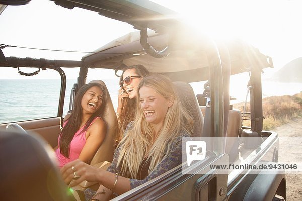 Three young women driving in jeep at coast  Malibu  California  USA