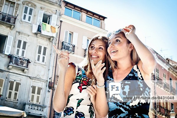 Zwei junge Freundinnen  die auf die Straße zeigen und nach oben schauen  Cagliari  Sardinien  Italien