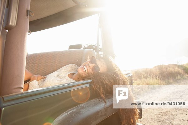 Porträt einer jungen Frau  die auf dem Rücksitz eines Jeeps an der Küste liegt  Malibu  Kalifornien  USA