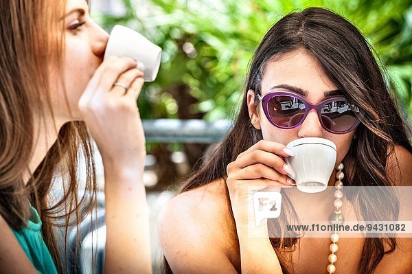 Nahaufnahme von zwei jungen Freundinnen beim Espresso-Trinken im Straßencafé  Cagliari  Sardinien  Italien