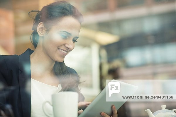 Young businesswoman using touchscreen on digital tablet in cafe London UK