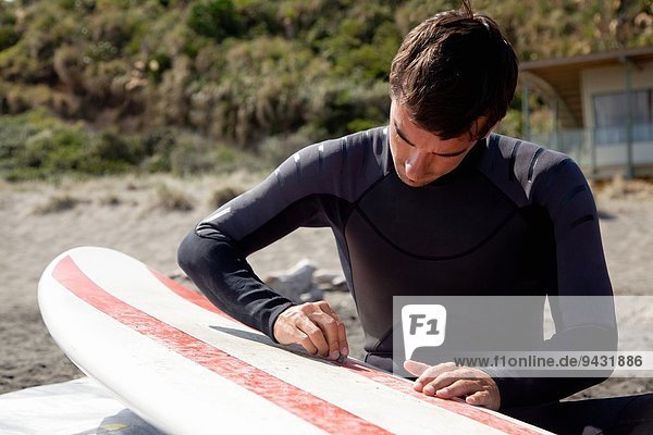 Junge erwachsene männliche Surfer Wachstafel