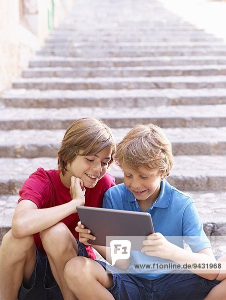 Brüder  die sich das digitale Tablett auf der Dorftreppe ansehen  Mallorca  Spanien