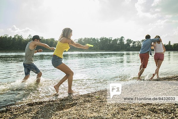 Friends playing with water pistols in lake