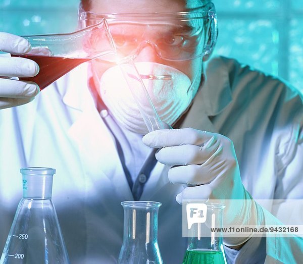 Chemiker gießt Flüssigkeit aus dem Becherglas in das Reagenzglas