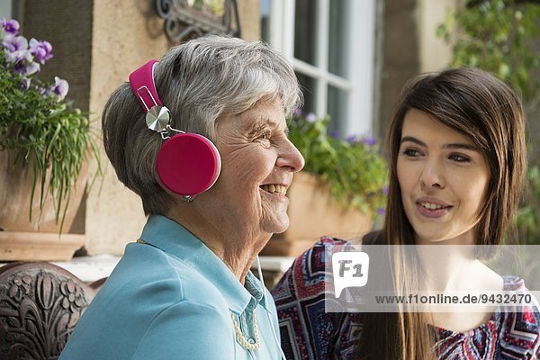 Seniorin mit Kopfhörer und Enkelin