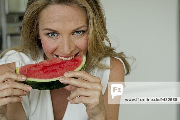 Reife Frau beißt Wassermelone