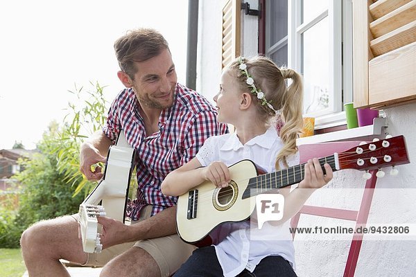 Girl playing guitar with father