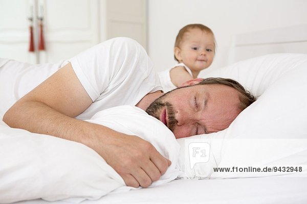 Vater schläft im Bett  Tochter schaut zu
