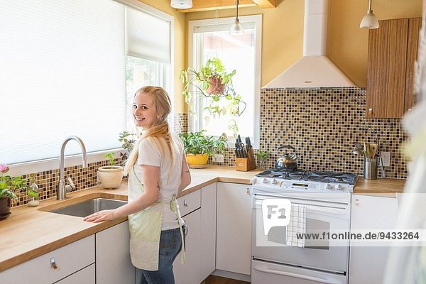 Junge Frau reinigt Küche mit grünen Reinigungsmitteln