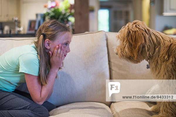 Junges Mädchen sitzend von Angesicht zu Angesicht mit Haushund