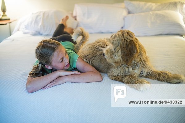 Junges Mädchen auf dem Bett neben dem Hund liegend