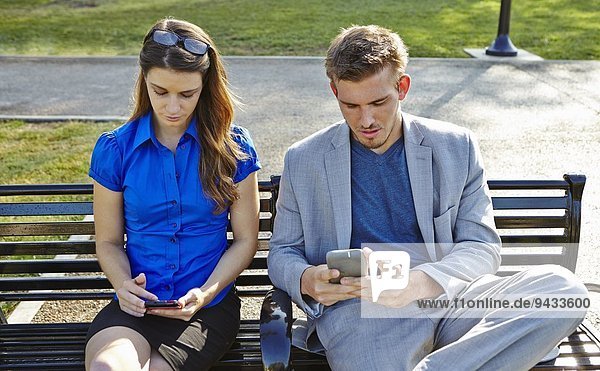 Geschäftsmann und Frau mit Smartphone im Park
