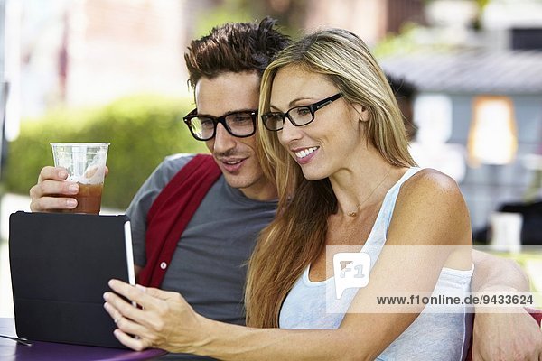 Couple using digital tablet at cafe