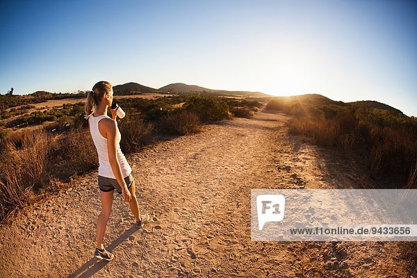 Young female jogger on path  drinking  Poway  CA  USA