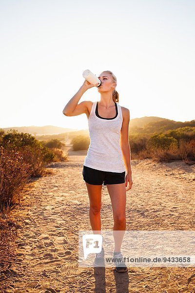 Female jogger drinking from water bottle  Poway  CA  USA