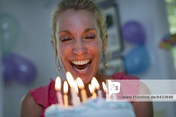Reife Frau mit Geburtstagskuchen und Kerzen