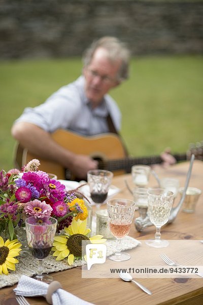 Tisch mit halbfertigen Getränken  reifer Mann spielt Gitarre im Hintergrund