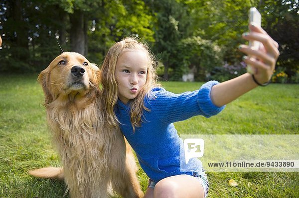 Mädchen nimmt Selfie mit Haustier Hund im Garten