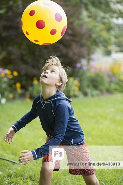 Junge spielt mit Ballspiel im Garten