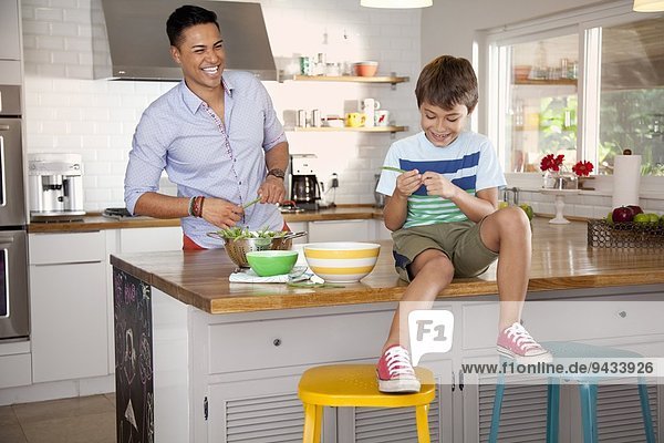 Father and son in kitchen  boy sitting on counter