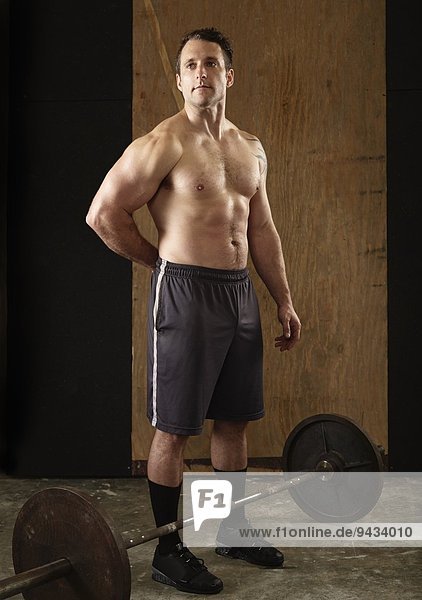 Porträt eines muskulösen männlichen Gewichthebers mit Langhantel in der Turnhalle