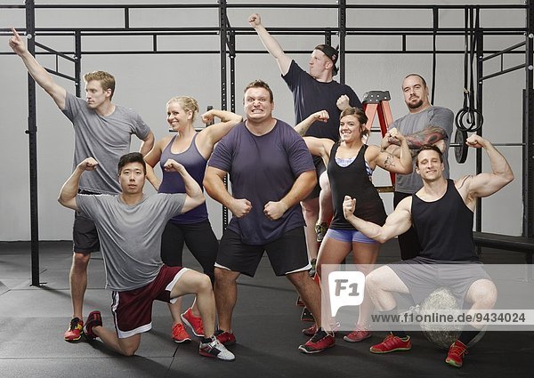 Porträt von acht Crossfit-Kollegen  die sich im Fitnessstudio bewegen