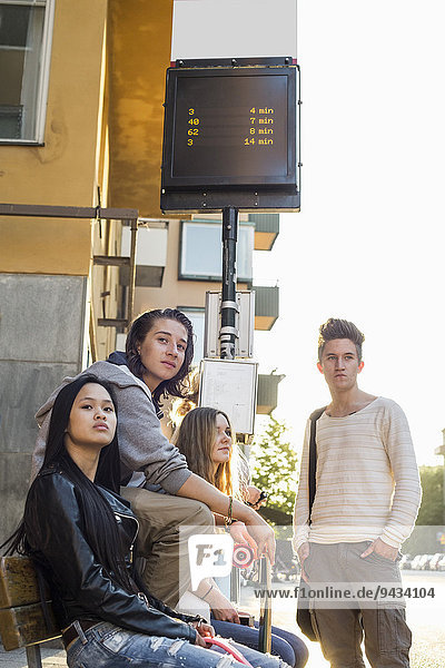 Multiethnic high school students waiting at bus stop